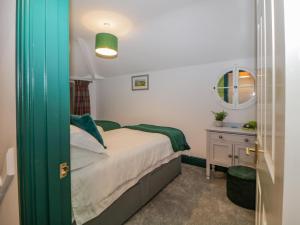 een kleine slaapkamer met een bed en een spiegel bij Herdwick Cottage in Brampton