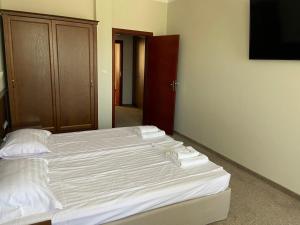 a bedroom with a bed with white sheets and a television at Villa Maria Revas in Sunny Beach