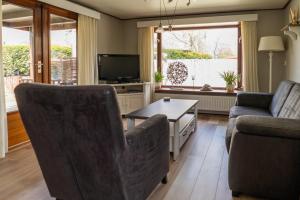 sala de estar con 2 sillas y TV en Drents Genieten - Struikheide met privé whirlpool, en Erm