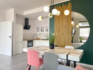 a kitchen with a table with pink chairs and a green wall at Apartamenty Bałtyckie - Bulwar Portowy - widok na port, centrum, najlepsza lokalizacja w Ustce in Ustka