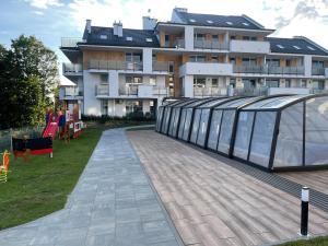 un grand bâtiment avec une passerelle en verre devant lui dans l'établissement Apartament z basenem i ogródkiem Baltic Sun A17, à Sztutowo