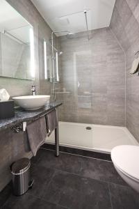 a bathroom with a sink and a tub and a toilet at Hotel Belvedere in Warnemünde