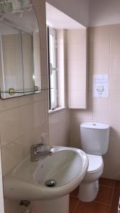 a bathroom with a sink and a toilet and a mirror at Sudoeste Guest House in Odeceixe