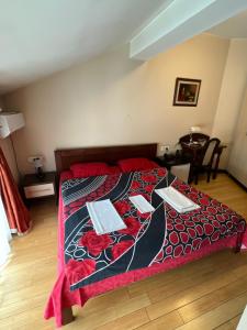 a bedroom with a bed with a red and black comforter at Hotel Royal in Bijelo Polje
