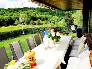 a white table with flowers on a patio at Chalet am Waldsee direkt am Badesee Rieden mit Seeblick für bis zu 14 Personen Traumferienhaeuser-Eifel in Rieden