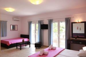 - une chambre avec deux lits et un lit rose dans l'établissement Dafni studios no2, à Parga