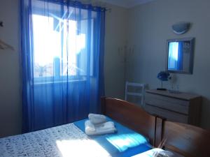 1 dormitorio con 1 cama con cortinas azules y ventana en Blue Moon GuestHouse, en Lagos