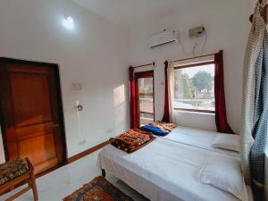 a small bedroom with two beds and a window at The Gupta Guest House in Bodh Gaya