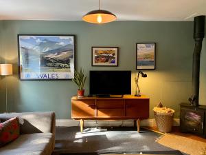 a living room with a tv on a wooden dresser at Ty'r Adar at Graig Wen in Arthog