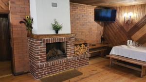 einen gemauerten Kamin in einem Zimmer mit einem Tisch und einem TV in der Unterkunft GRĪVIŅU pirts in Liepa