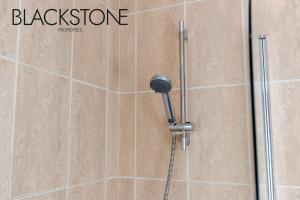 a shower with a black shower head on a tiled wall at Cheerful one-bedroom house, with on-street parking by BPNE in Darlington