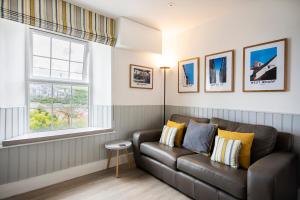 a living room with a couch and two windows at Seafarers, Mevagissey - Coastguard Cottage overlooking harbour in Mevagissey