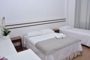 a hotel room with two beds and a mirror at Avenida Hotel in São Lourenço do Oeste