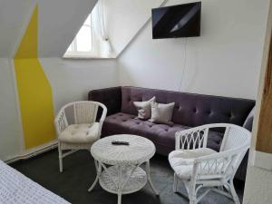 a living room with a purple couch and two chairs and a table at Pension Schmidt in Schierke