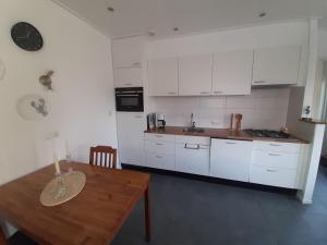a kitchen with white cabinets and a wooden table at Appartement Boomgaard in Vrouwenpolder