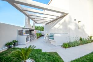 a patio with a pergola and a table and bench at Grande Mandi & Jani Villa in Laganas