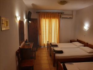 a room with four beds and a desk and a window at Hotel Kosmas in Sarti