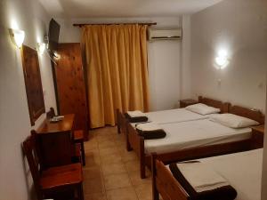a room with two beds and a table and chairs at Hotel Kosmas in Sarti