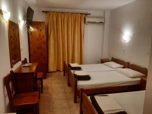 a room with two beds and a table and chairs at Hotel Kosmas in Sarti