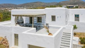 een wit huis met witte trappen en tafels aan de zijkant bij Hercules house pyrgaki paros in Drios