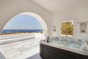 a bathroom with a soaking tub with a view of the ocean at Hercules house pyrgaki paros in Drios