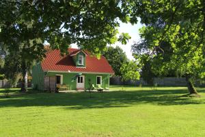 a green house with a red roof in a field at Ferien in Troja in Lärz