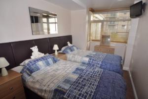 um quarto com 2 camas e um urso de peluche sentado numa mesa em Vista Apartments, Goodrington Beach, Paignton em Paignton