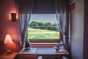 フロロンヴィルにあるHotel Au Coeur de Lacuisineの野原の景色を望む窓付きの部屋
