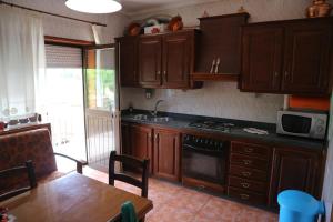 a kitchen with wooden cabinets and a table and a stove at Alojamento, Chelas Rural AL in Mirandela