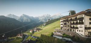 budynek na wzgórzu z górami w tle w obiekcie Kronplatz-Resort Hotel Kristall w mieście Valdaora