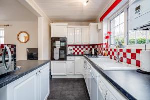een keuken met witte kasten en rode en witte geruite tegels bij MPL Apartments - Woodside House by Harry Potter Studios in Watford