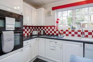 una cocina con armarios blancos y paredes a cuadros rojo y blanco en MPL Apartments - Woodside House by Harry Potter Studios en Watford