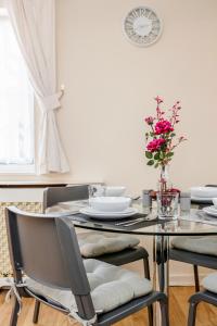 een eetkamer met een tafel en stoelen en een klok bij MPL Apartments - Woodside House by Harry Potter Studios in Watford