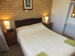 a bedroom with a bed and two night stands with lamps at Sunrise Units in Hervey Bay