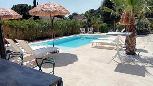 einen Pool mit Stühlen und Sonnenschirmen neben einem Resort in der Unterkunft VILLA RASOA chambre LOVE in Cap d'Agde