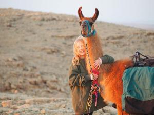 Eine Frau, die neben einem kleinen Kamel steht. in der Unterkunft Alpaca Farm - חוות האלפקות in Mitzpe Ramon