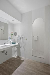 a white bathroom with a sink and a shower at Hotel Juwel in Bad Füssing