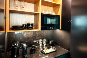 a kitchen with a counter with glasses and a microwave at Golden Eye Apartament Seaside Park in Kołobrzeg
