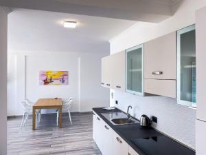 eine Küche mit weißen Schränken und einem Holztisch in der Unterkunft Appartamento Fronte Mare 20 in Portoferraio