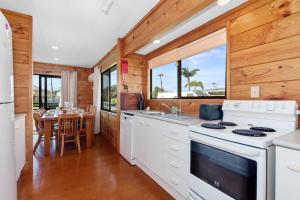 uma cozinha com paredes de madeira, electrodomésticos brancos e uma mesa em Karaka Bach - Mangawhai Heads Holiday Home em Mangawhai