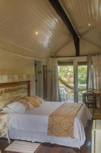 a bedroom with a large bed and a balcony at Pousada Casa Da Colina in Santo Antônio do Pinhal