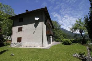 um edifício branco com um telhado preto num campo de relva em Trentino Val Rendena casa con vista 3 camere doppie e 2 bagni em Groppe de Fora