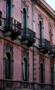 a pink building with windows and balconies on it at L'Antico Palazzo rooms in Catania