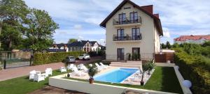 a villa with a swimming pool and a house at Pensjonat SPA Dolce Vita in Ustronie Morskie