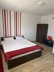 a bedroom with a bed with a red and white striped wall at Casa de la Corbu in Corbu