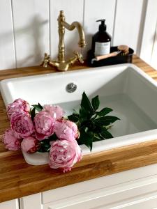 a white sink with pink flowers in it at Ragnar Glamp Milzkalne Lux in Rauda