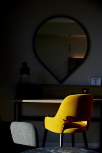einem gelben Stuhl vor einem Tisch mit einem Spiegel in der Unterkunft Tŷ Milford Waterfront in Milford Haven