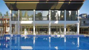 a building with a swimming pool with white tables and chairs at Bitez Garden Life in Bitez