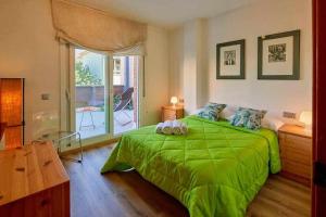 una camera da letto con un letto verde e una grande finestra di Apartamento con gran terraza en Girona a Girona