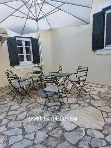 a patio with a table and chairs and an umbrella at Corfu Cottage Sfrayda in Sinarádes